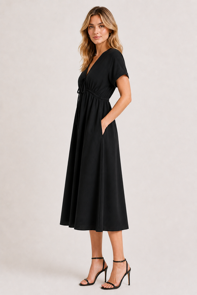 Model standing against a white studio background wearing the black onyx Sabine midi.